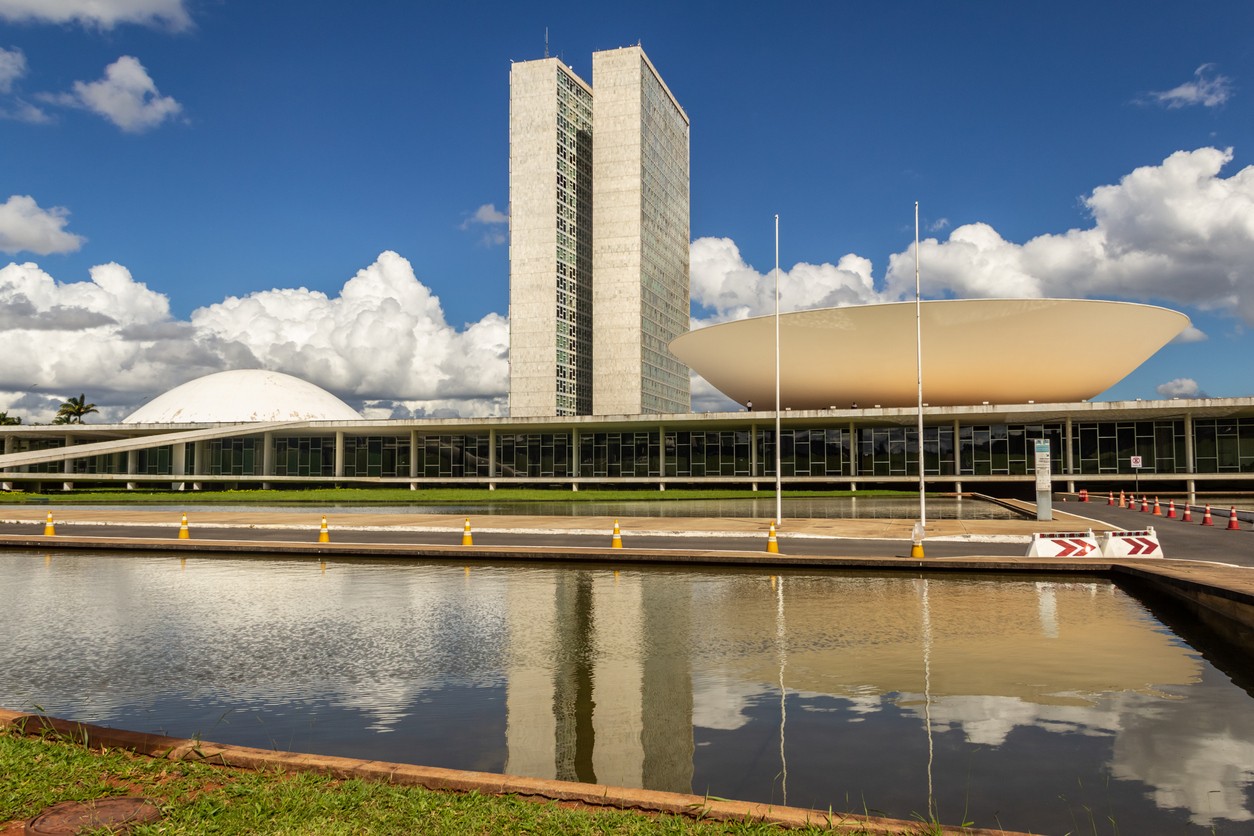 Brasilia, Federal District, Brazil – December 25, 2021: National Congress Palace with reflection in the water mirror, on a clear day with cloudy sky. The National Congress Palace is a work of architect Oscar Niemeyer.
