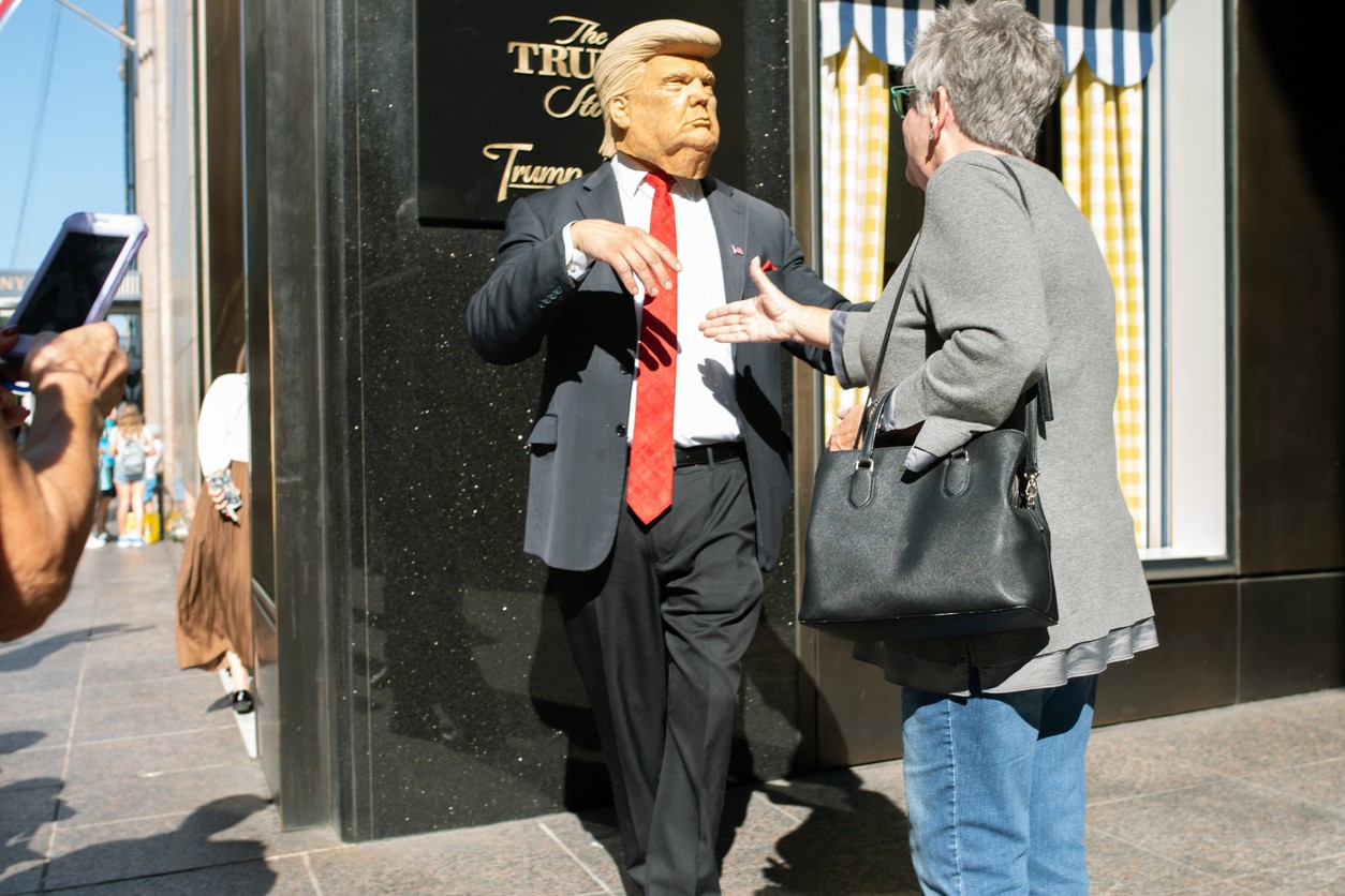 A Donald Trump impersonation performer shakes hands with a woman outside of Trump Tower in Manhattan, New York City in exchange for money