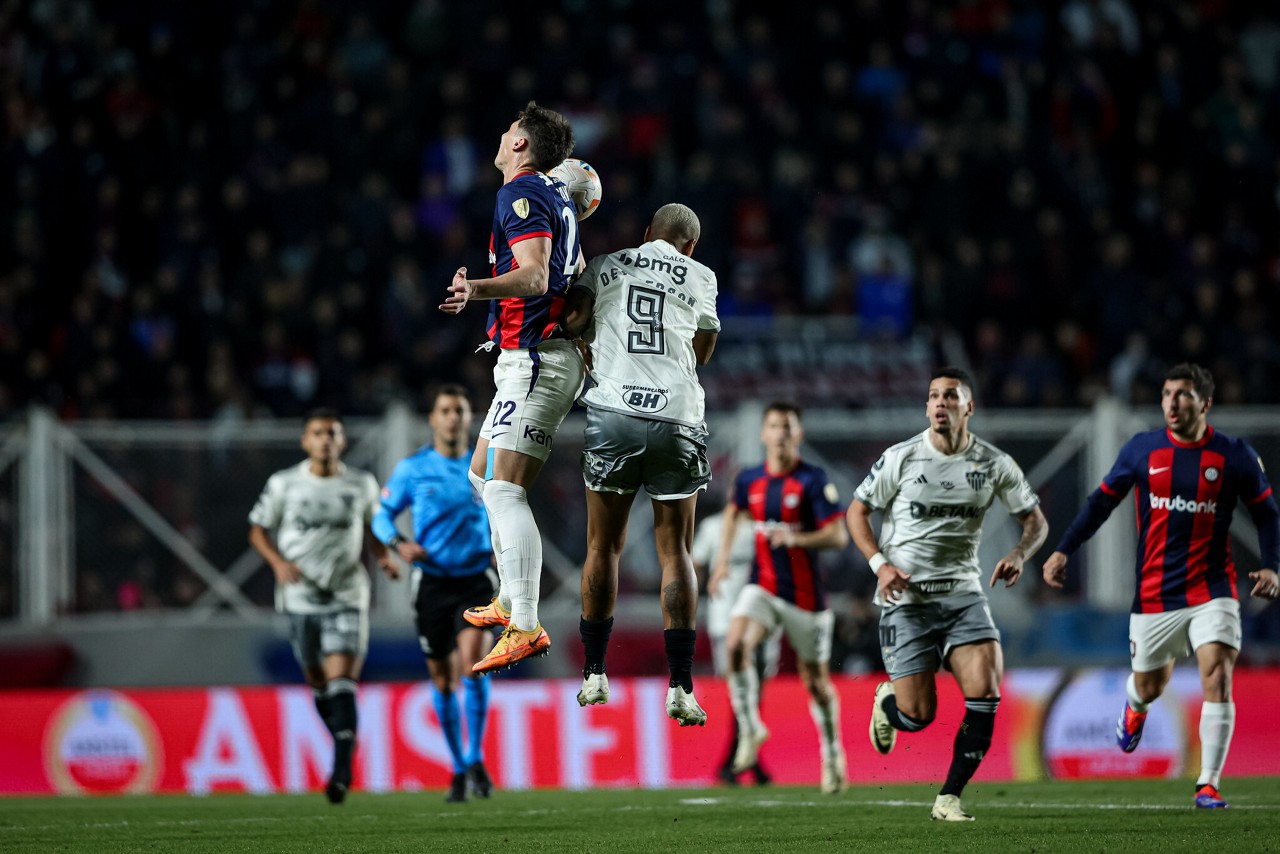 Deyverson sobe para disputar bola com jogador do San Lorenzo, diante do estádio Nuevo Gasómetro lotado
