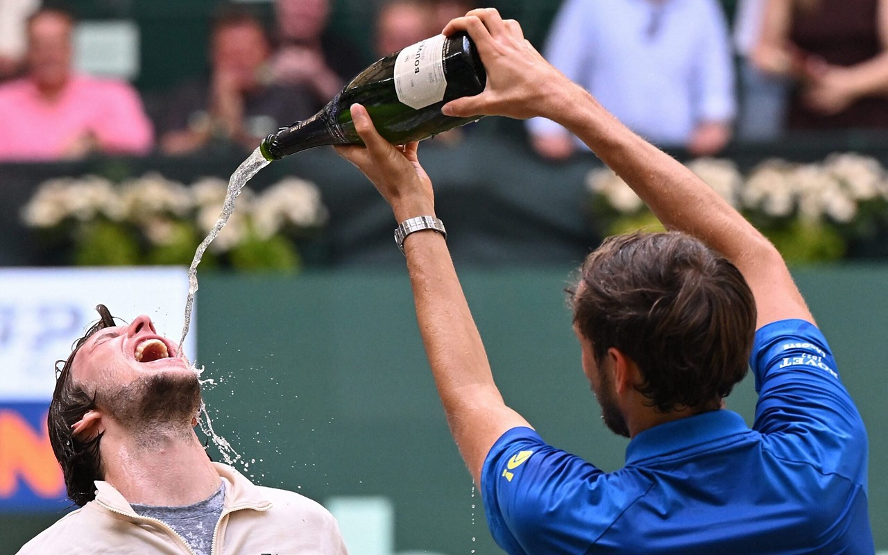 Alexander Bublik comemora o título de Halle bebendo champanhe do russo Daniil Medvedev (Foto: CARMEN JASPERSEN / AFP)