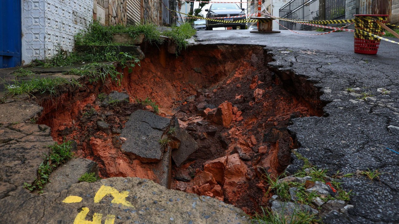 Por causa das chuvas, o asfalto cedeu e abriu um buraco ao lado da calçada, no domingo (22)