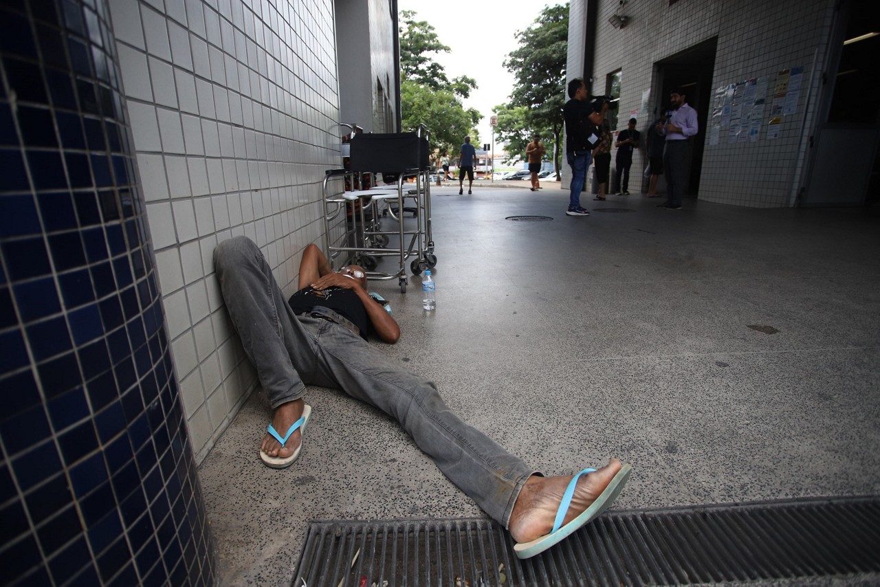 Jorge Eduardo Pinto, de 63 anos, aguarda atendimento deitado sobre um pedaço de papelão na porta do pronto-socorro