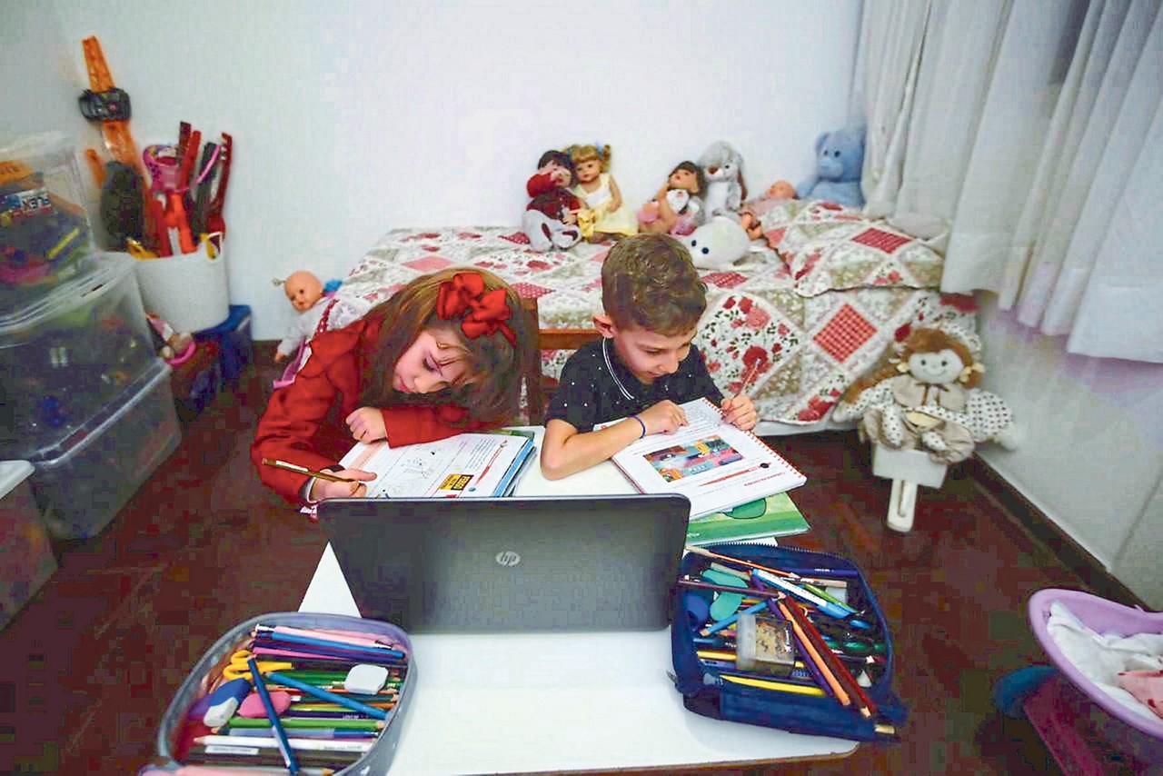 Os gêmeos Maria Luiza e João Pedro Pinheiro, 7, comemoram o descanso das aulas remotas; eles entram de férias hoje