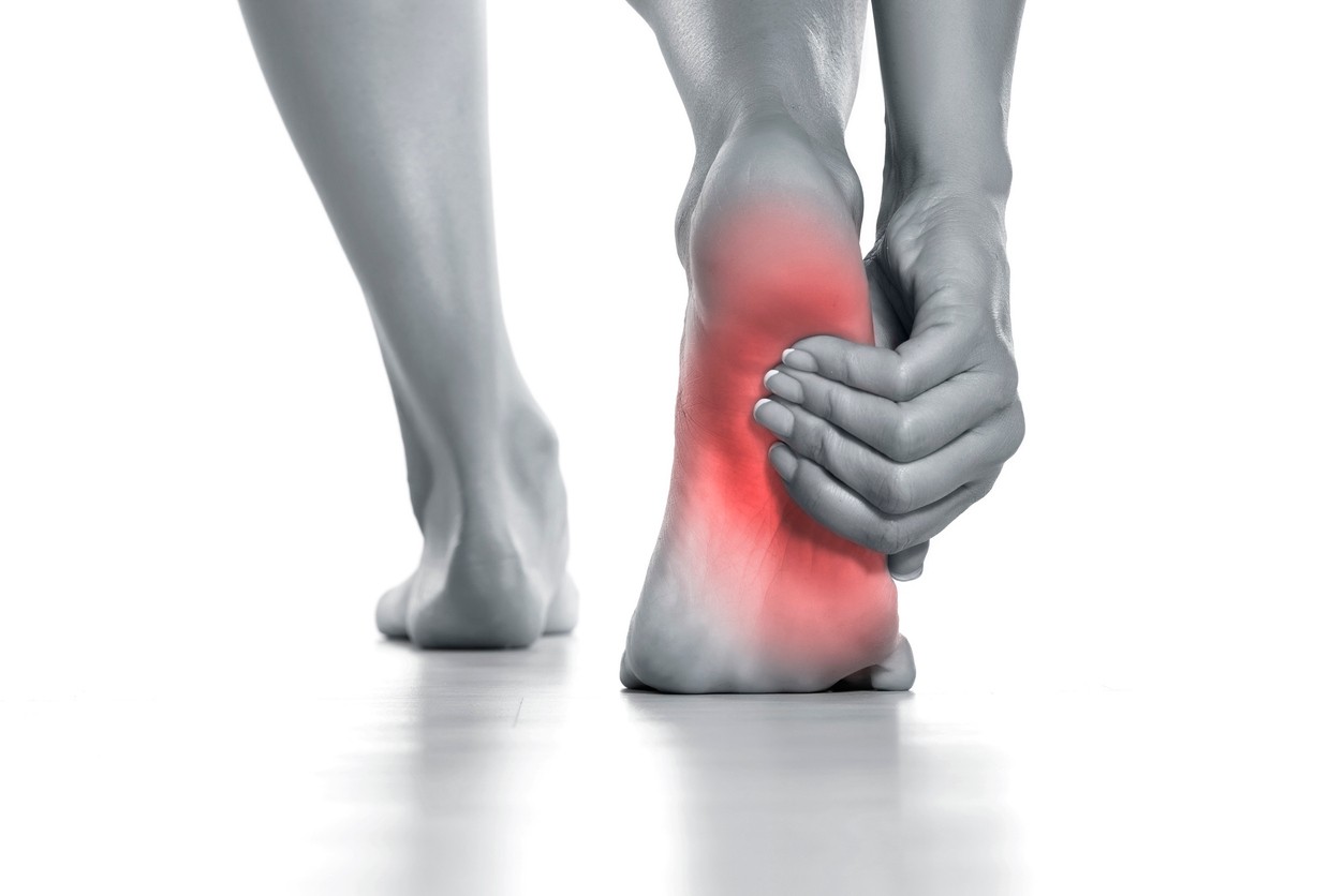 woman holding her painful foot on white background
