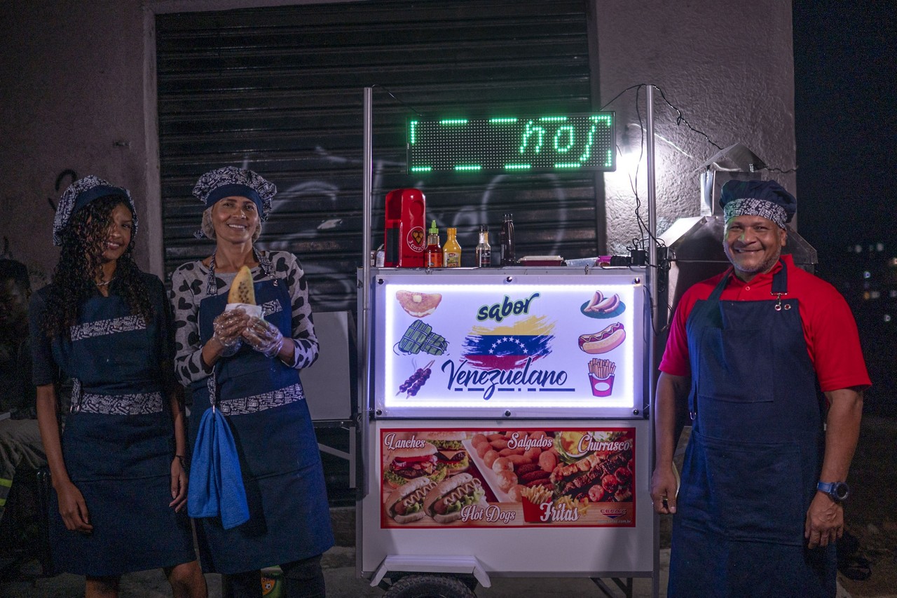 Família de venezuelanos vende empanadas e cachorro-quente em um carrinho no bairro Ouro Preto