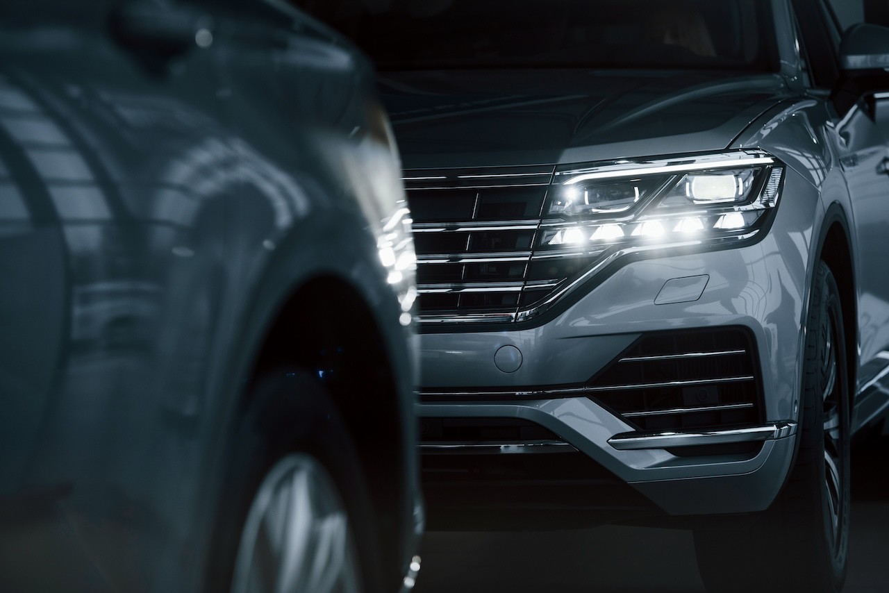 Powerful headlights. Particle view of modern luxury cars parked indoors at daytime.