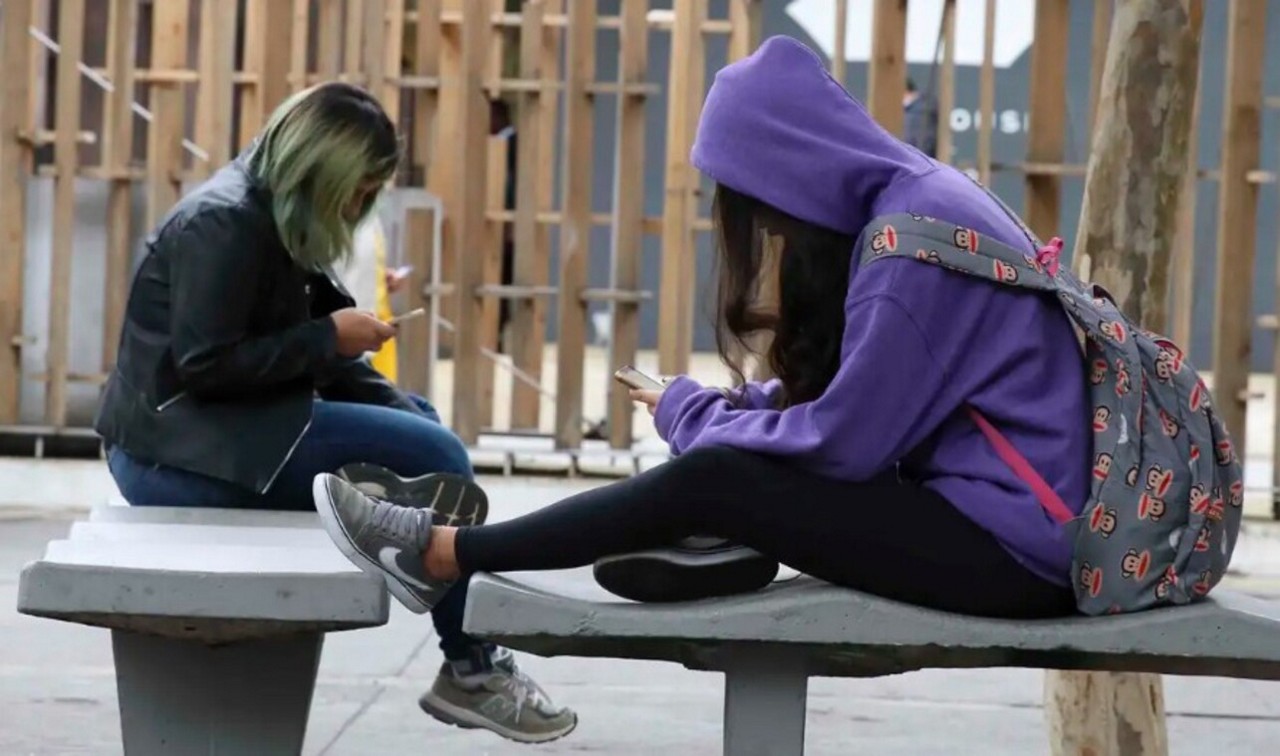 Jovens estudantes utilizam celulares no intervalo de aula
