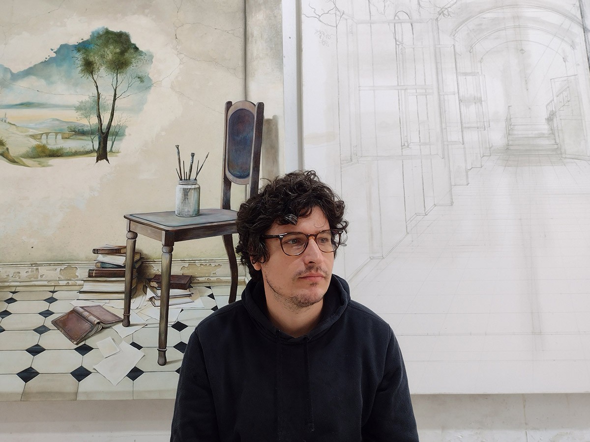 O artista Andrey Rossi a frente de pinturas feitas por ele