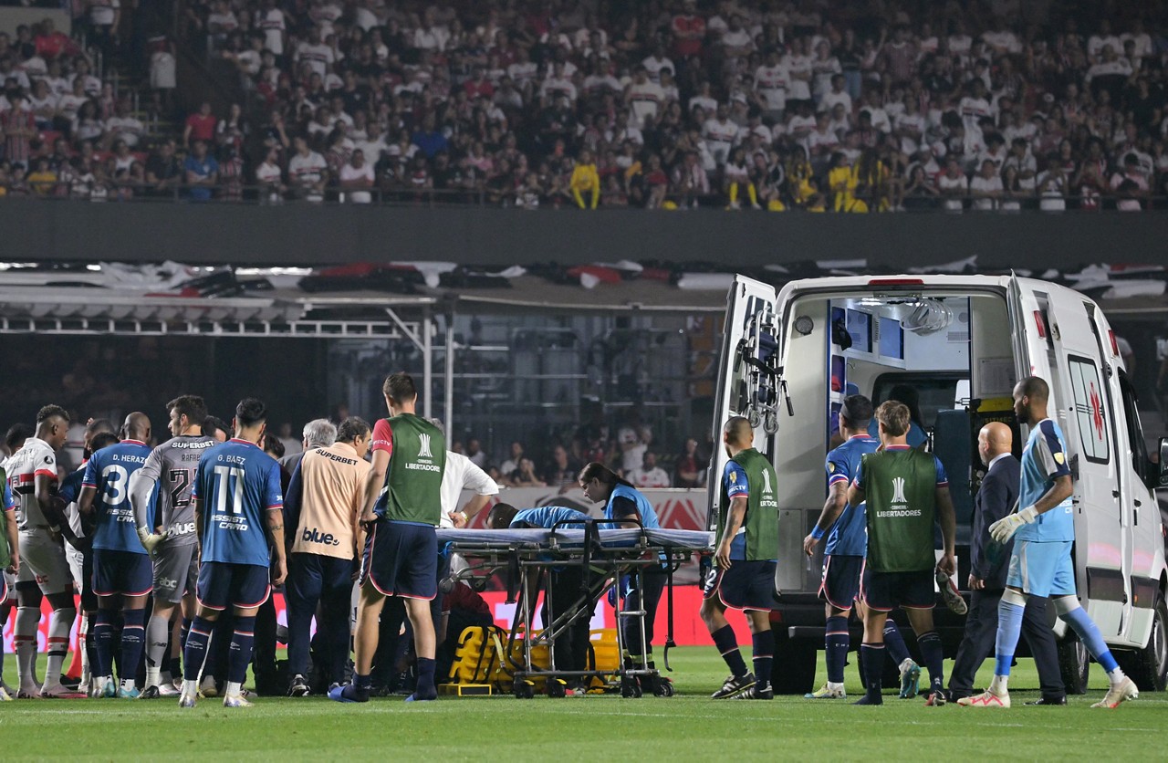 Nacional's defender Juan Manuel Izquierdo (covered) receives medical attention after fainting during the Copa Libertadores round of 16 second leg football match between Brazil's Sao Paulo and Uruguay's Nacional at the MorumBIS stadium in Sao Paulo, Brazil, on August 22, 2024. (Photo by NELSON ALMEIDA / AFP)