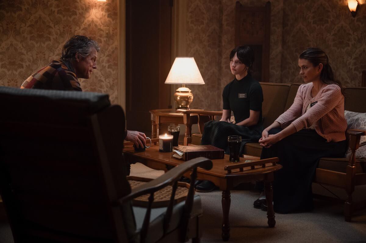 As irmãs Barnes (Sophie Thatcher) e Paxton (Chloe East) apresentando a palavra Mórmon ao sr. Reed (Hugh Grant).