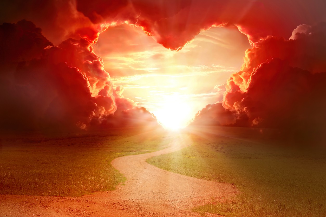 Red heart shaped sky at sunset. Beautiful landscape with road.Love background with copy space. Road to love
