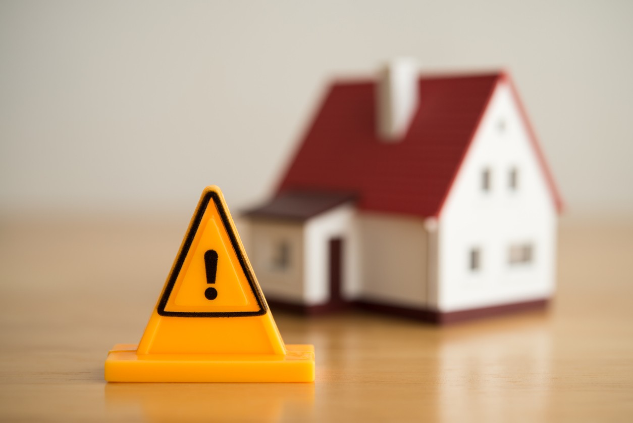 Emergency notification warning sign label with model house background. Mortgage loan for buying home or real estate property, money risk management in financial, foreclosure and bankruptcy  concept.