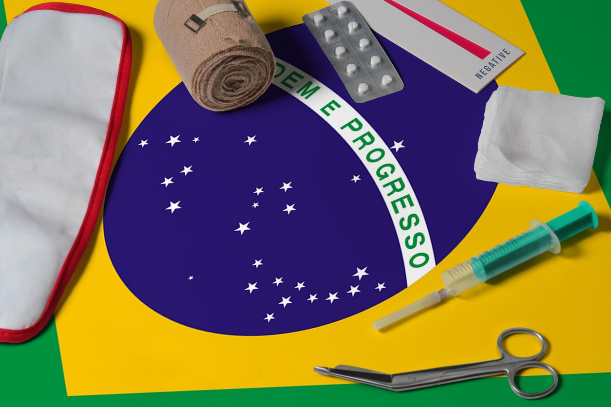 Brazil flag with first aid medical kit on wooden table background. National healthcare system concept, medical theme.