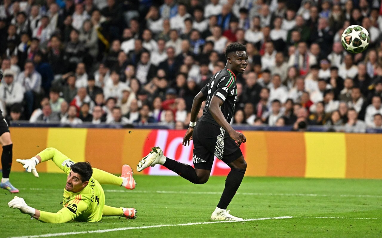 Saka toca por cima de Courtois para abrir o placar para o Arsenal contra o Real Madrid, na Champions League (Foto: Javier Soriano/AFP)