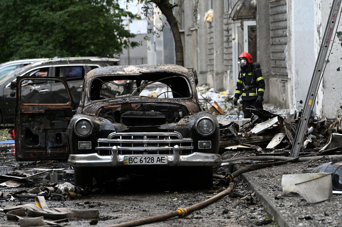 A firefighter stands next to a burnt-out car following mass Russian drone and missile strikes in the western Ukrainian city of Lviv on July 12, 2025, amid the Russian invasion of Ukraine. (Photo by YURIY DYACHYSHYN / AFP)