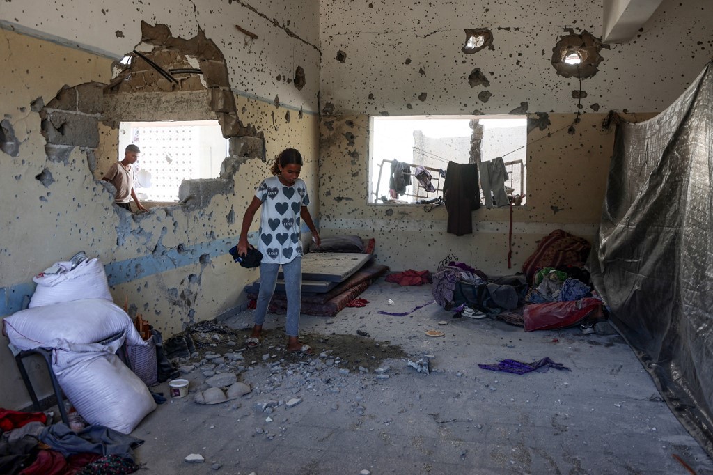 Jovem palestina analisa destruição em uma escola de Gaza após bombardeio