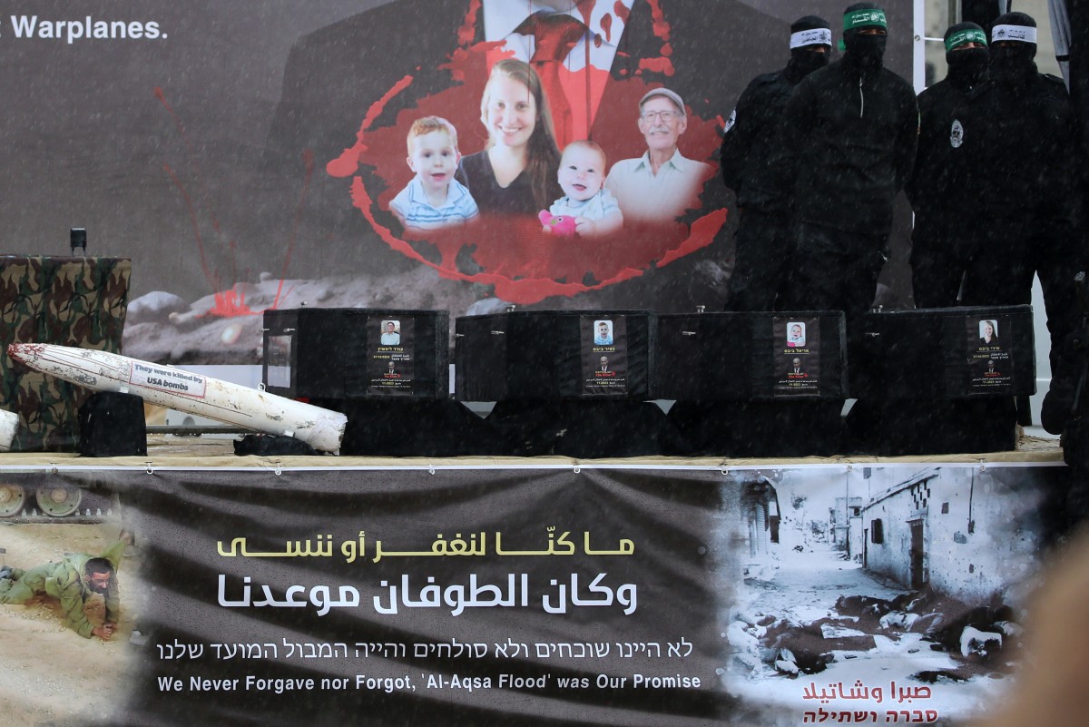 Combatentes do Hamas em um palco ao lado dos caixões