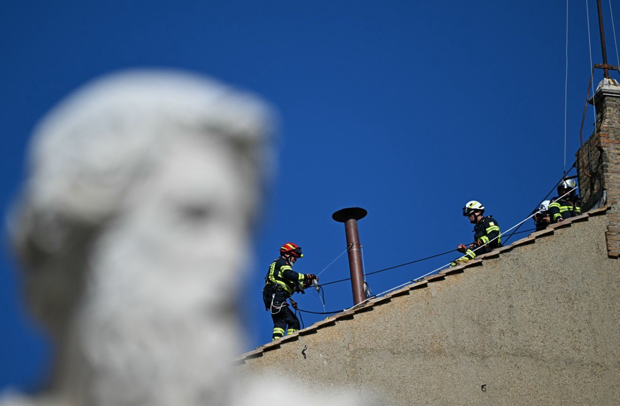 Bombeiros instalam chaminé na capela Sistina. Em primeiro plano, está uma estátua de São Paulo