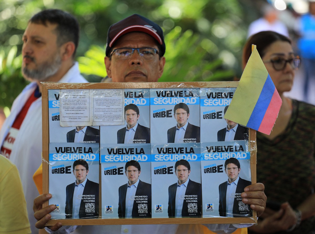 Em protesto contra a violência, homem segura um cartaz com propaganda do pré-candidato à presidência na Colômbia, baleado no sábado (7)