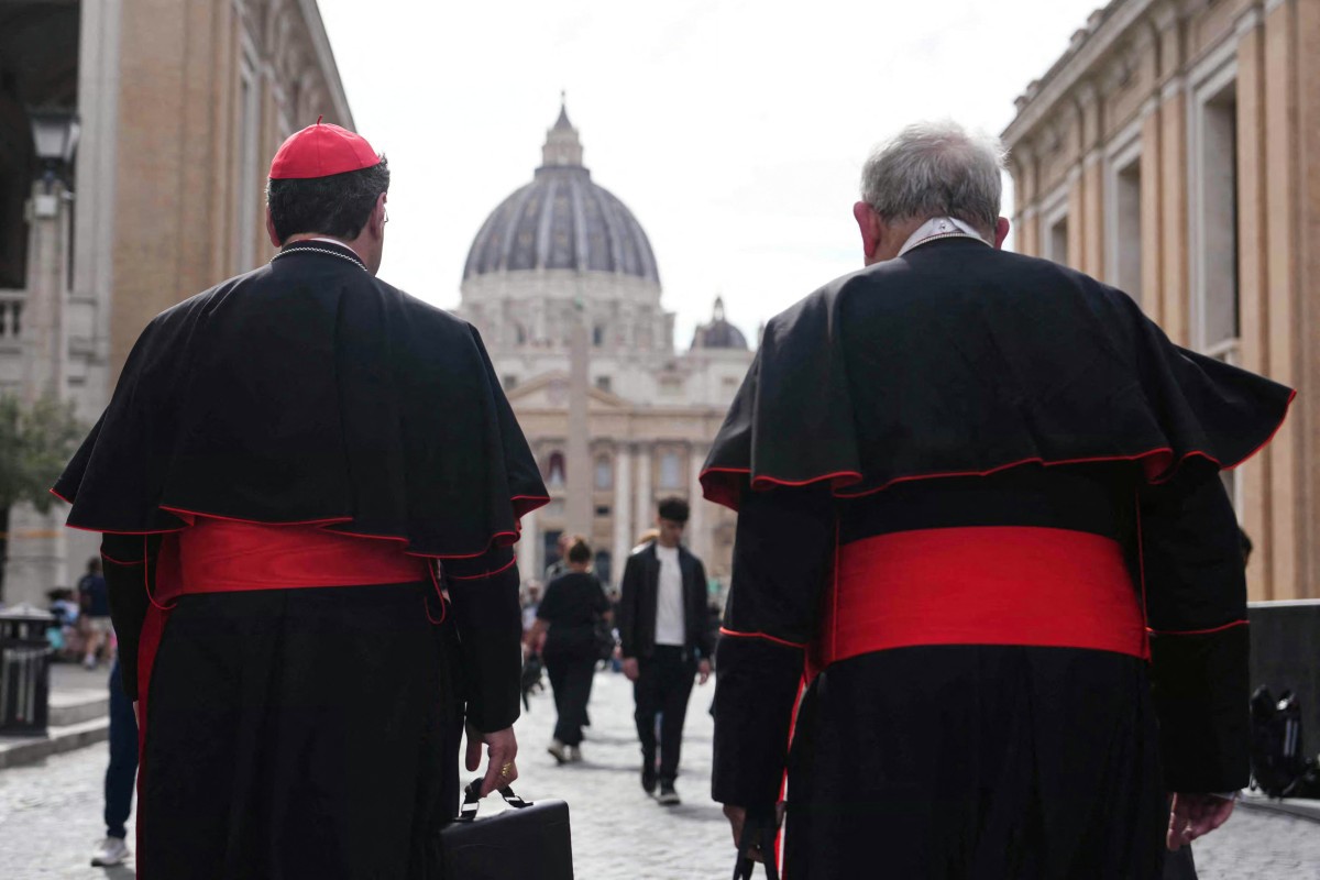 Cardeais caminham na Via della Conciliazione, perto do Vaticano, com a Basílica de São Pedro ao fundo