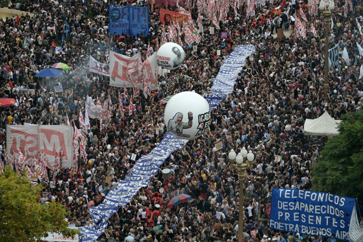 Um balão com um retrato de Nora Cortinas é visto no meio da multidão enquanto as pessoas se reúnem para lembrar o 49º aniversário do golpe militar de 1976