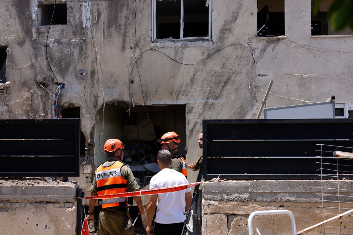 Socorristas e bombeiros observam danos em prédio atingido em Beit She'an, Israel (Jalaa Marey/AFP)