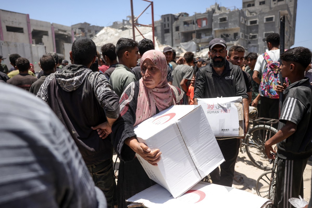 Palestinos carregam cestas básicas doadas pelo Crescente Vermelho dos Emirados