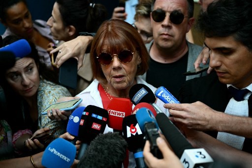 Gisele P. (ao centro) escoltada por seu advogado e um de seus filhos fala à mídia ao sair do tribunal 