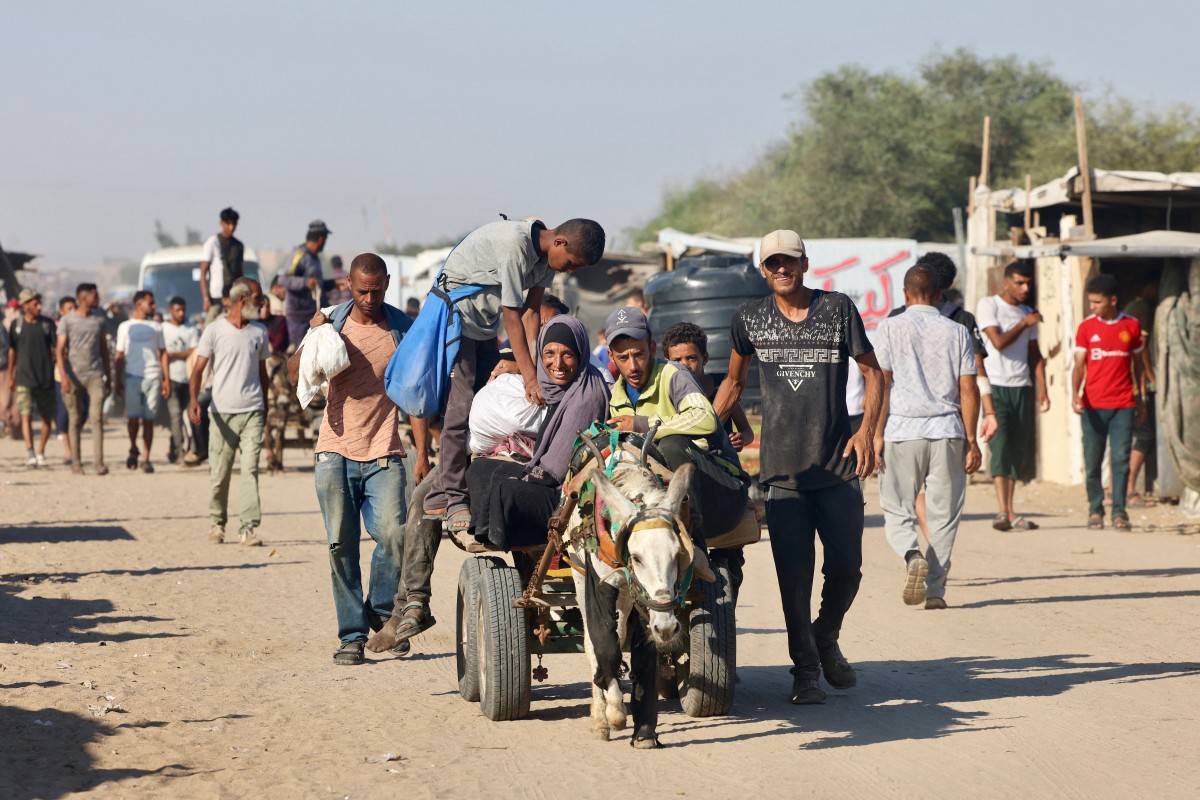 Palestinos chegam à área de Mawasi, em Rafah, em 24 de julho de 2025, após receberem ajuda humanitária de um ponto de distribuição