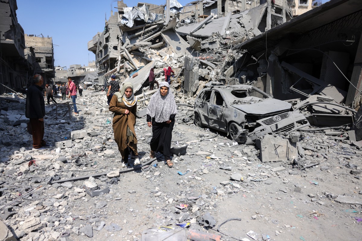 Palestinos caminham em meio a escombros pós-bombardeios em Gaza