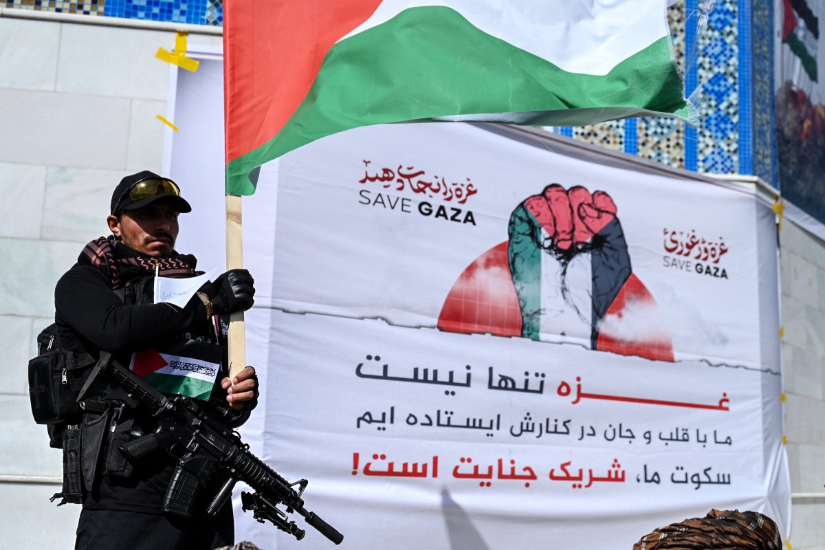 Um agente de segurança do Talibã segura uma bandeira nacional palestina durante um protesto anti-Israel após as orações de sexta-feira, 30