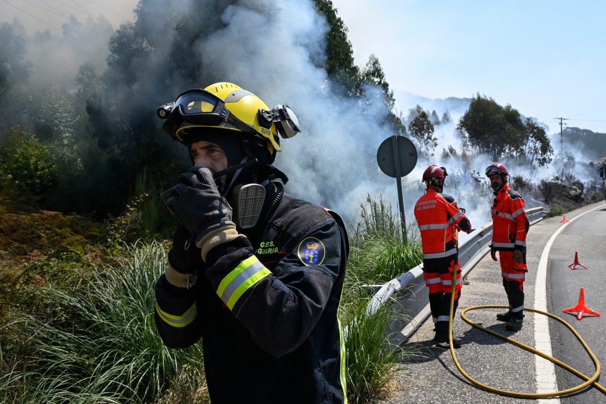 Firefighters try to control a wildfire near the village of Mougas, in Oia municipality, northwestern Spain on August 22, 2025. The northwestern regions of Galicia and Castile and Leon, along with Extremadura in the west, have been hit hardest by the fires raging since early August in the scorching heat. More than 403,000 hectares (996,000 acres) have been burnt in Spain this year, according to the European Forest Fire Information System. (Photo by MIGUEL RIOPA / AFP)