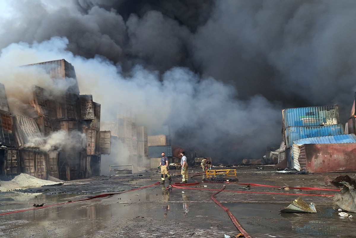 Bombeiros e equipes de resgate trabalham no local de uma explosão que ocorreu no dia anterior no píer do porto Shahid Rajaee, a sudoeste de Bandar Abbas, na província de Hormozgan, no Irã