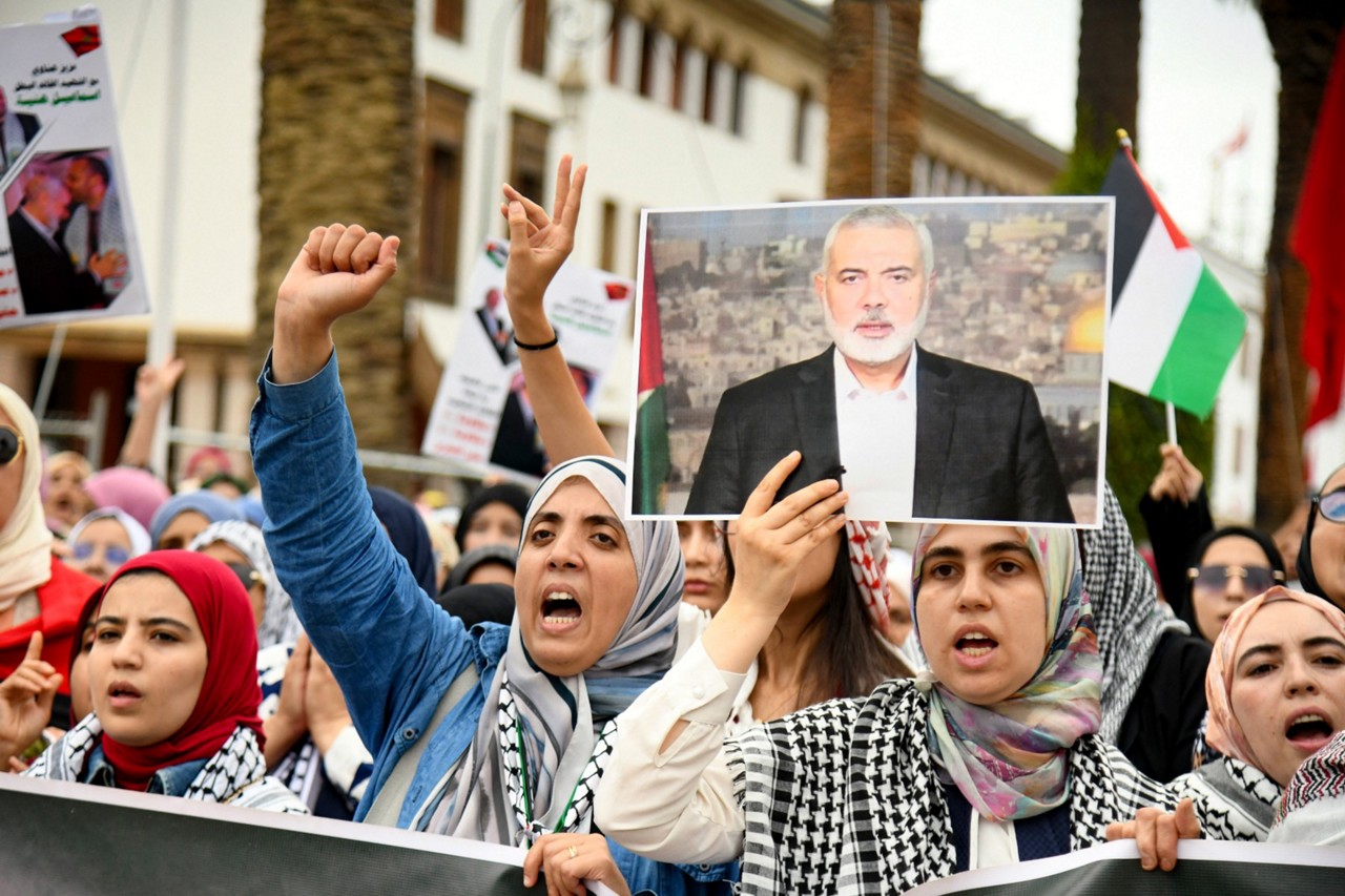 Mulheres levantam um retrato do líder assassinado do Hamas, Ismail Haniyeh, durante um protesto