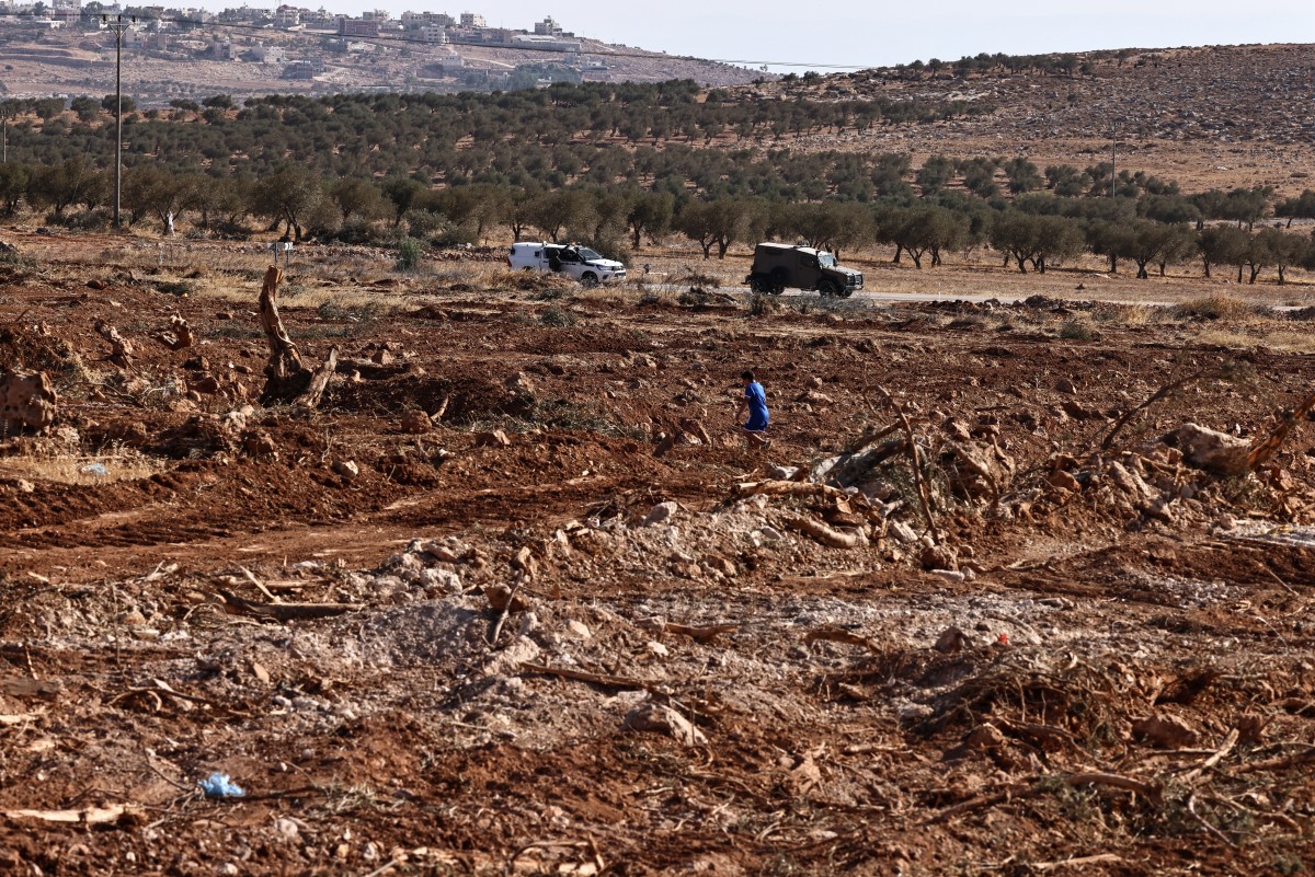 Um garoto palestino observa soldados israelenses patrulhando perto de uma área onde, segundo relatos, eles derrubaram oliveiras com escavadeiras para limpar o terreno na vila ocupada de Al-Mughayyir, ao norte de Ramallah, na Cisjordânia
