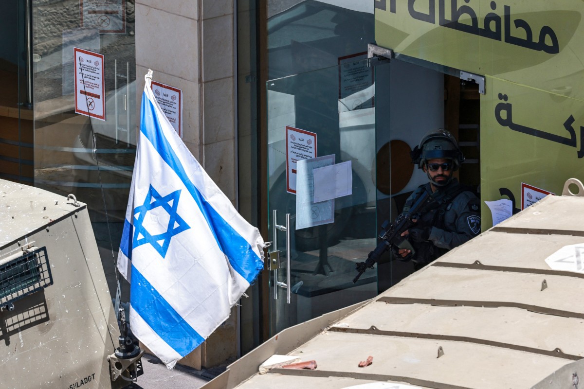 Soldado israelense em um banco na Cisjordânia ocupada | Foto: Zain Jaafar/AFP