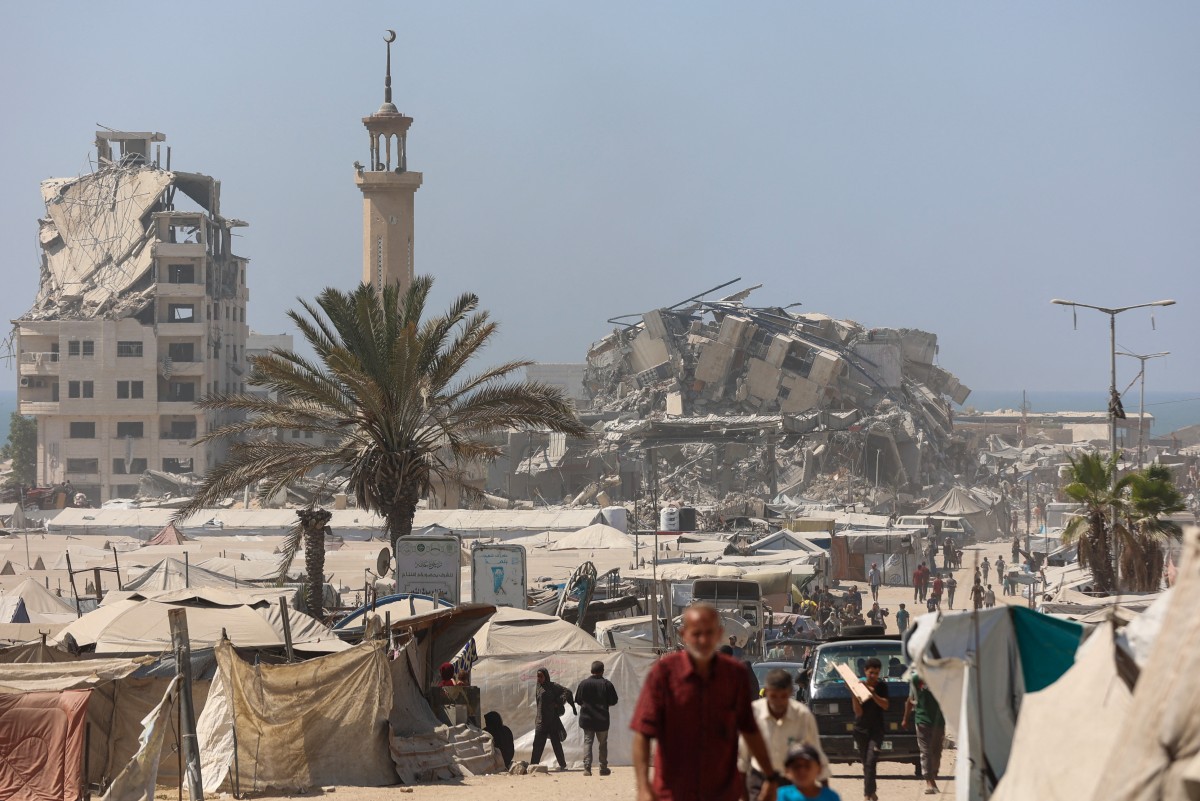 Palestinos passam perto dos destroços da Torre Mushtaha na Cidade de Gaza 
