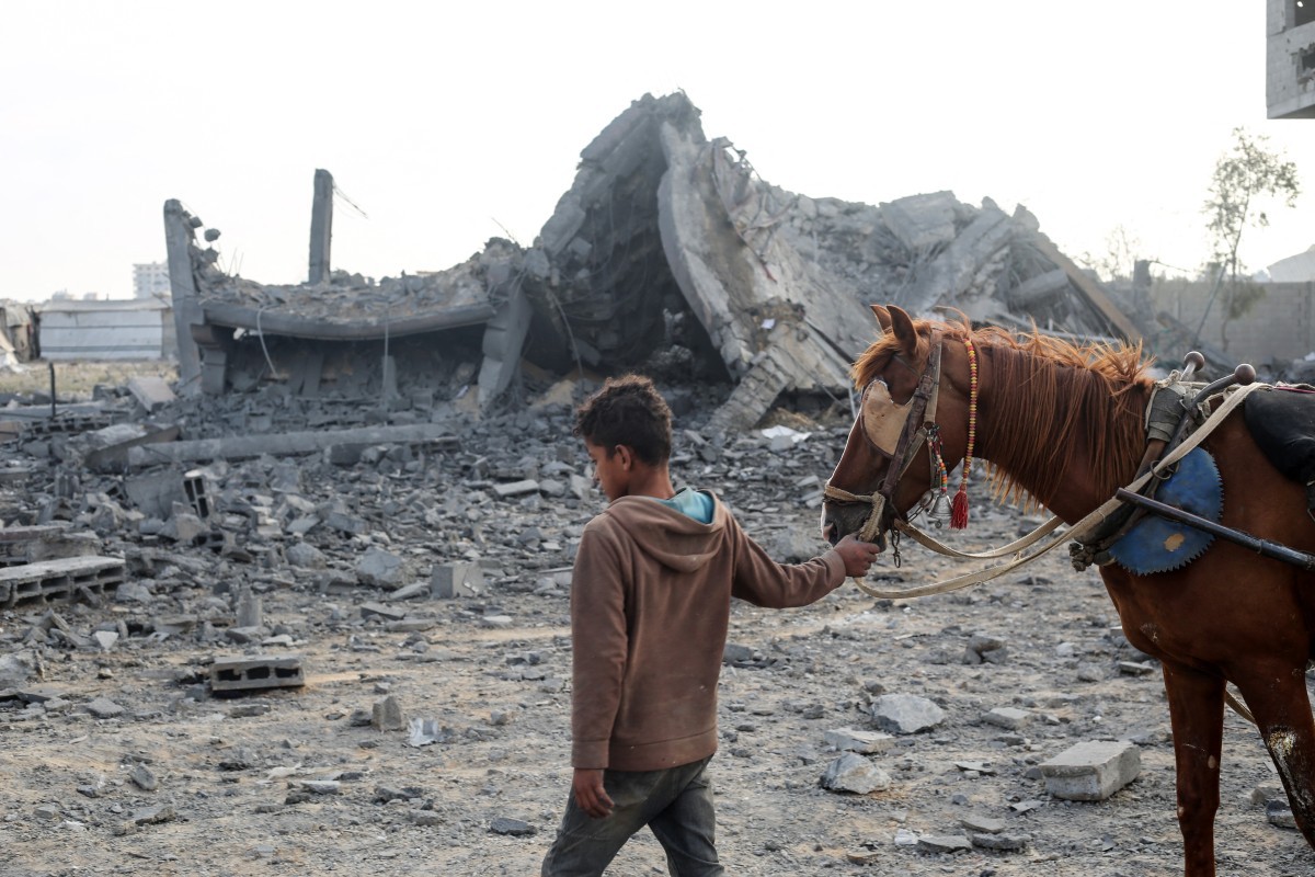Menino palestino caminha com cavalo por área destruída em Gaza