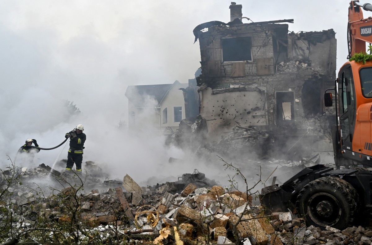 Bombeiros apagam incêndio em casas danificadas após ataque russo na região de Kiev em 25 de maio de 2025