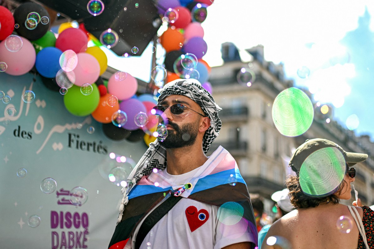 A person wears a keffiyeh and a rainbow flag while taking part in a Paris Pride parade on June 28, 2025. (Photo by Julie SEBADELHA / AFP)