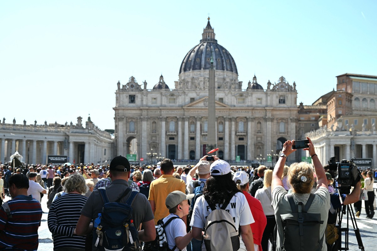 Visitors gather near St Peter's Square, with St Peter's basilica in the background, a day after the Pope's death, at the Vatican on April 22, 2025. The Pope died of a stroke, the Vatican announced hours after the death on April 21, 2025, of the 88-year-old reformer who inspired devotion but riled traditionalists during 12 years leading the Catholic Church. (Photo by Alberto PIZZOLI / AFP)