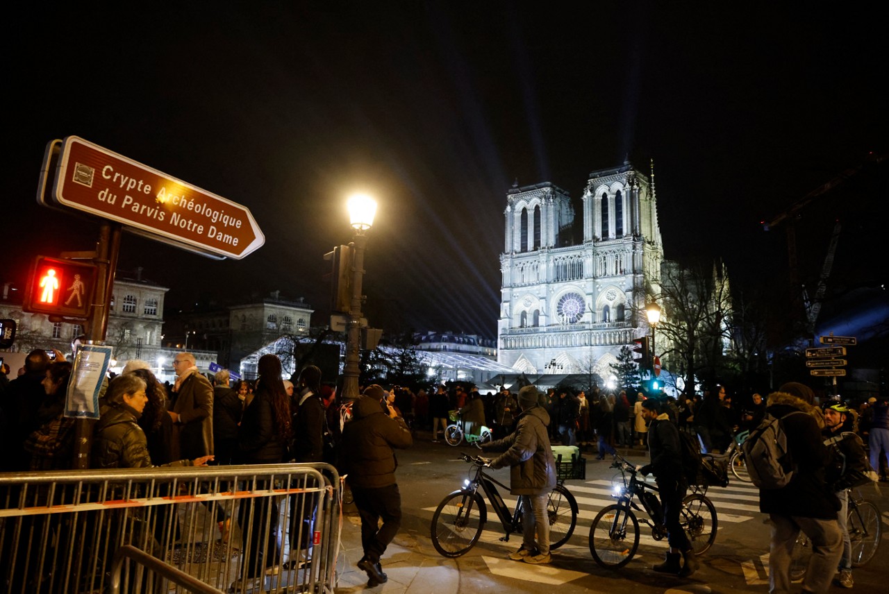 Pessoas se reúnem em frente à Catedral de Notre-Dame de Paris, na véspera de sua reabertura oficial