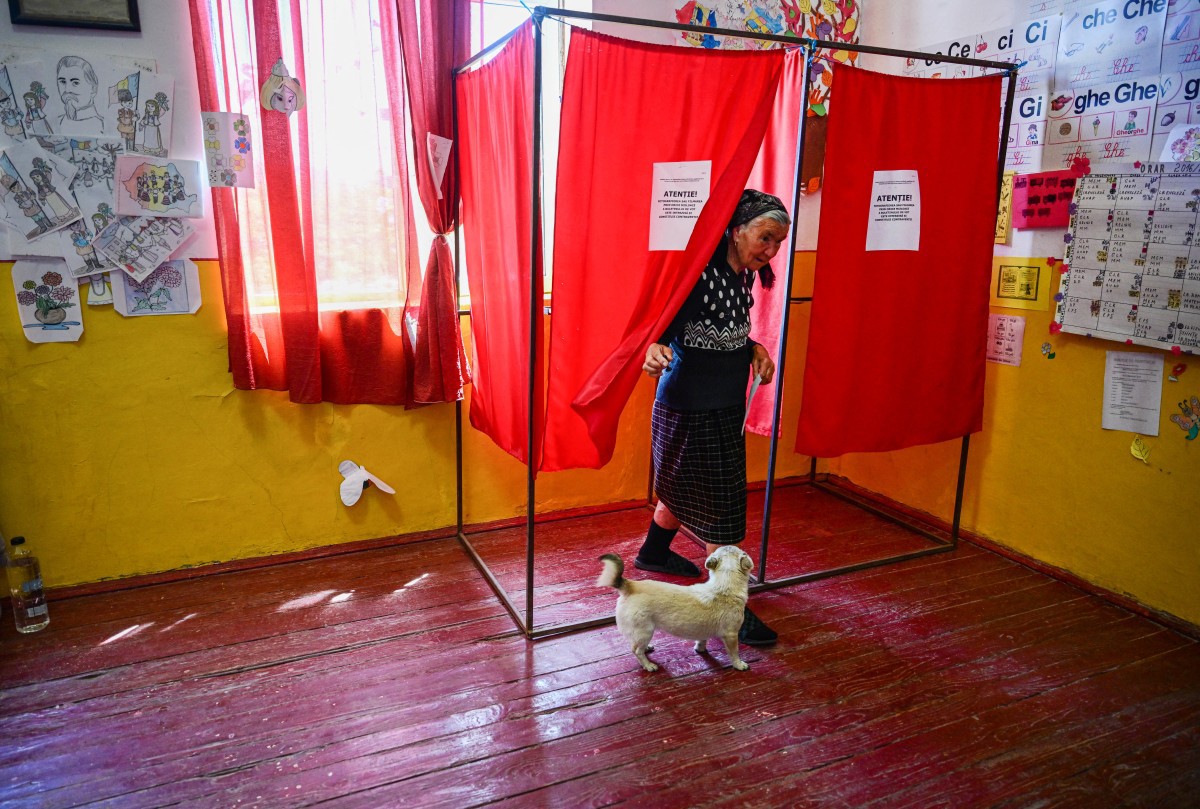 Uma mulher sai de uma cabine de votação em uma seção eleitoral na vila de Popesti, na Romênia