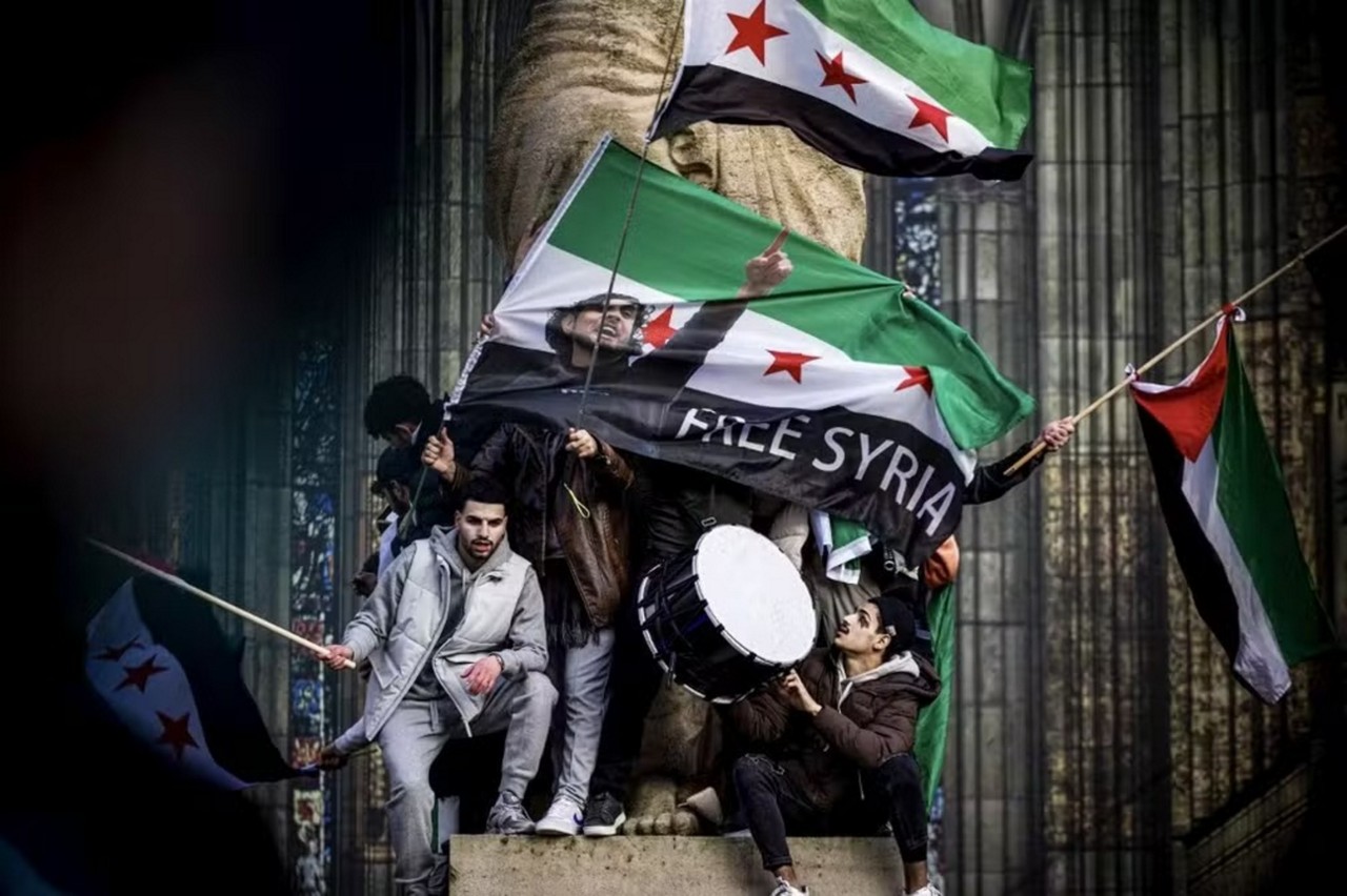 Membros da comunidade síria agitam bandeiras nacionais da Síria durante uma manifestação perto de Domplein para celebrar o fim do regime do ditador sírio Bashar al-Assad

