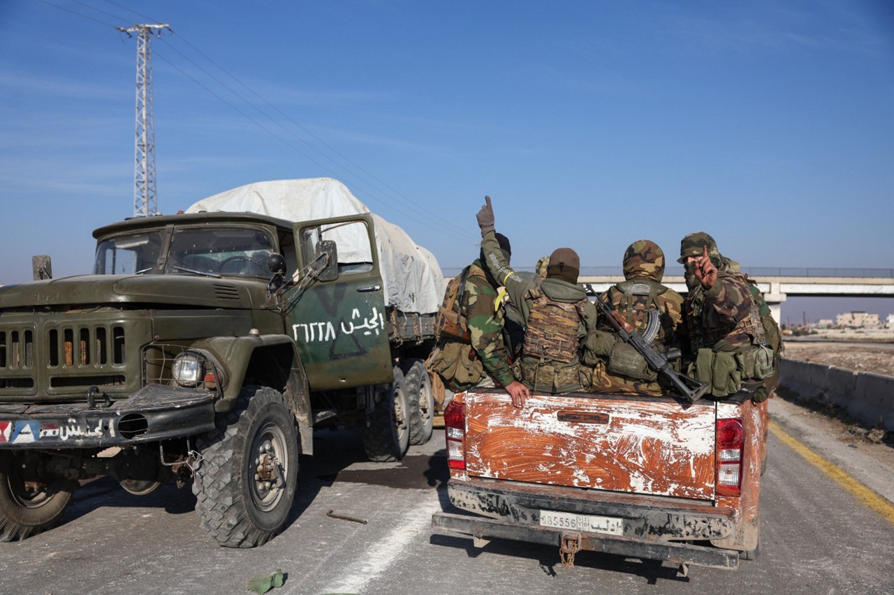 Combatentes antigovernamentais tomam posse de equipamentos militares e veículos do exército sírio que foram abandonados na rodovia para Damasco, ao chegarem à cidade de Suran, ao norte da cidade de Hama, na Síria