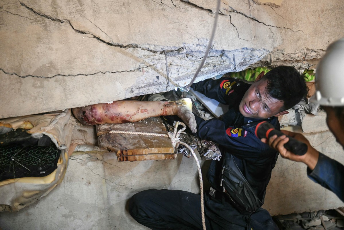 Socorrista tenta libertar sobrevivente preso em meio a escombros em Mandalay, Mianmar,(Photo by Sai Aung MAIN  AFP)