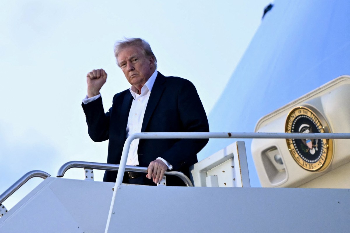 US President Donald Trump raises a fist as he steps off Air Force One at Palm Beach International Airport in West Palm Beach, Florida, on April 11, 2025. Trump is heading to Palm Beach to spend the weekend at his Mar-a-Lago resort. (Photo by Mandel NGAN / AFP)
