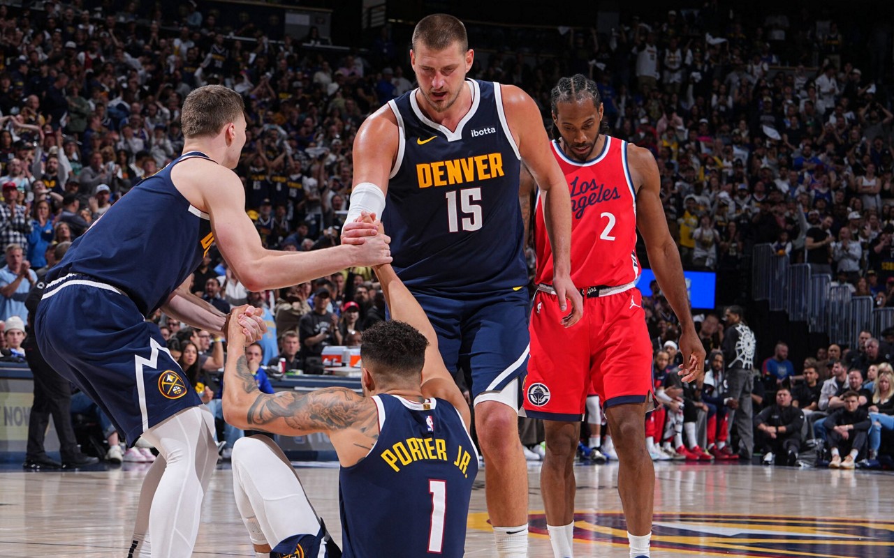 Nikola Jokic e Christian Braun ajudando Michael Porter Jr. a se levantar em jogo entre Nuggets e Clippers pelos playoffs da NBA 2024/25 (Foto: Garrett Ellwood/NBAE via Getty Images/AFP)