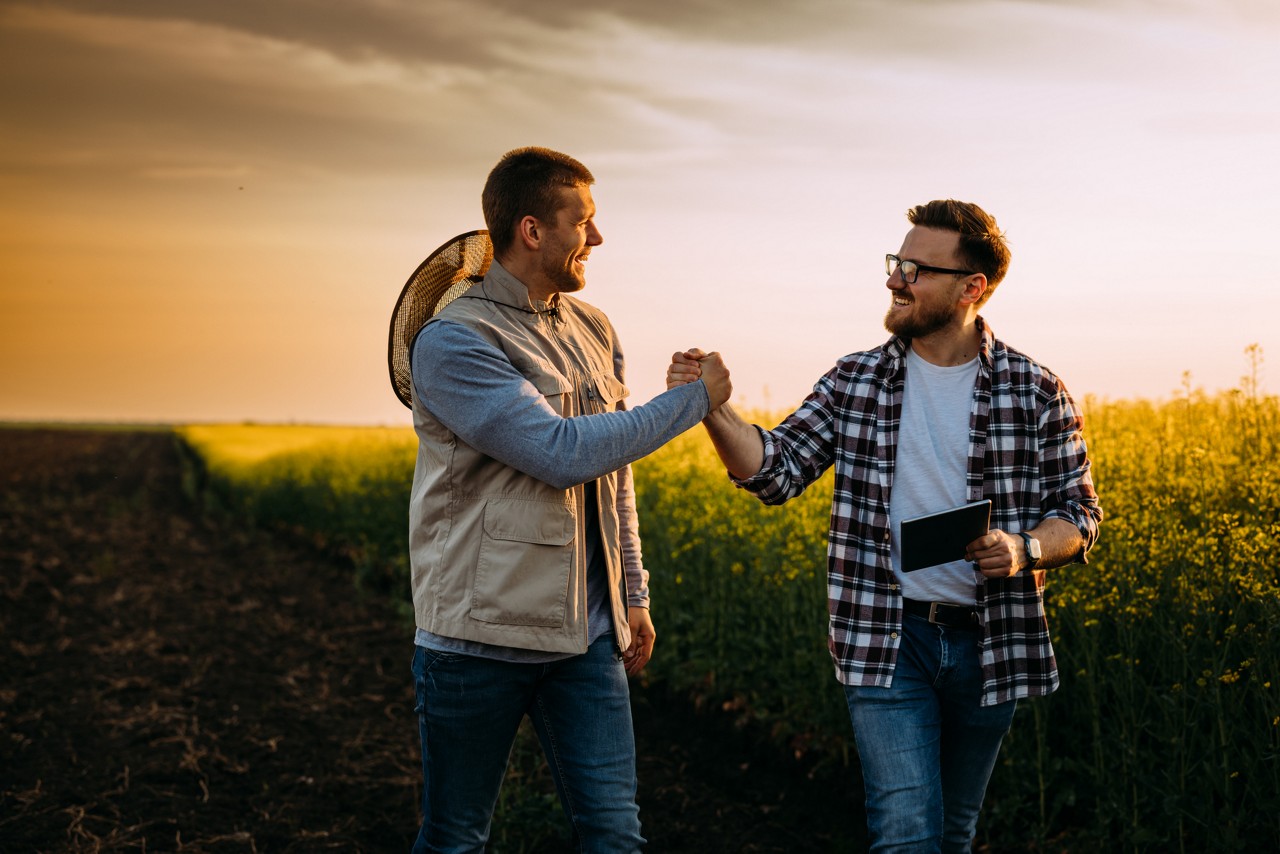 A Farmer and his business partner greet each other on the field