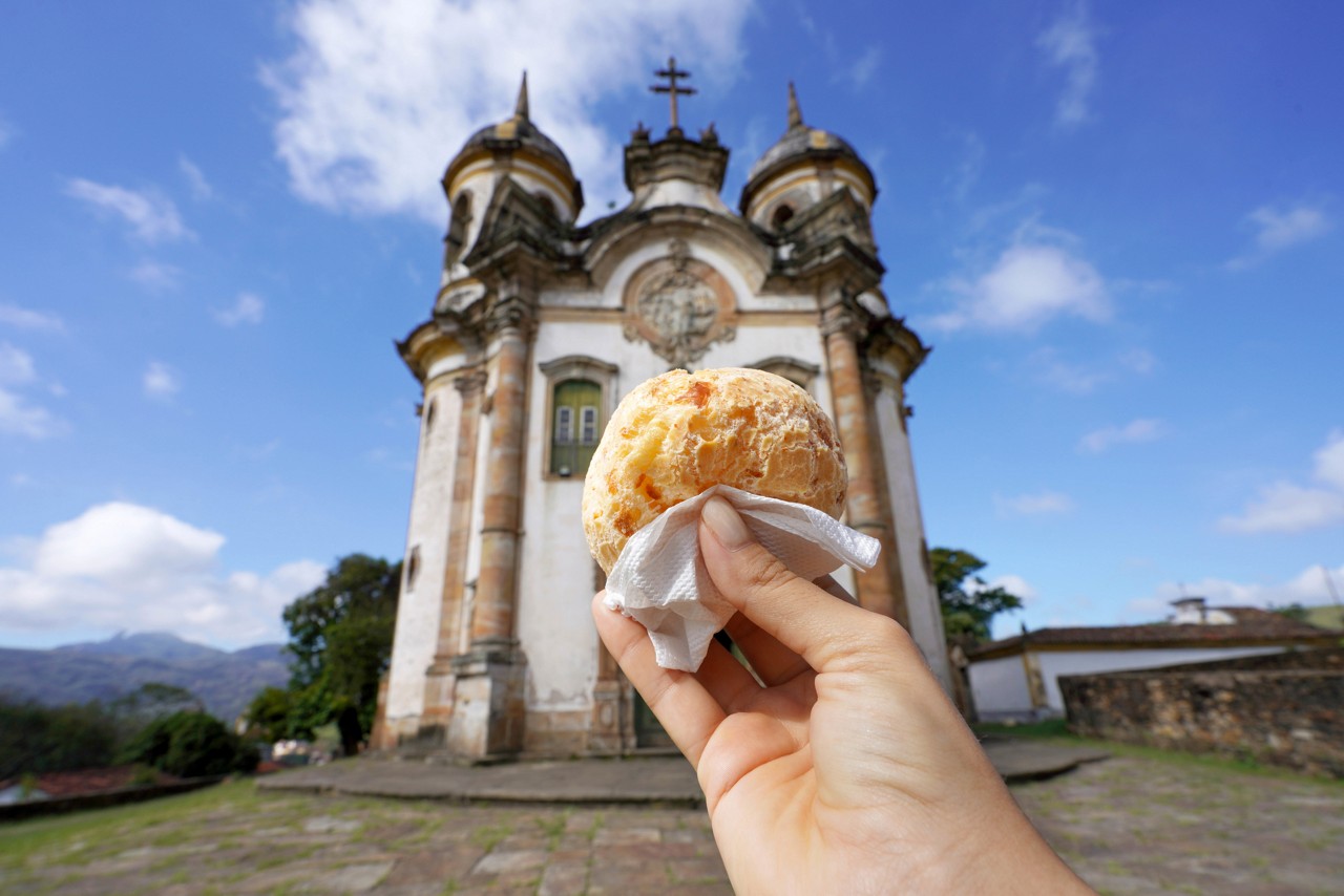 Pao de queijo (Brazilian cheese bun) with the church of St. Francis of Assisi in Ouro Preto, Minas Gerais, Brazil, the city is World Heritage Site by UNESCO